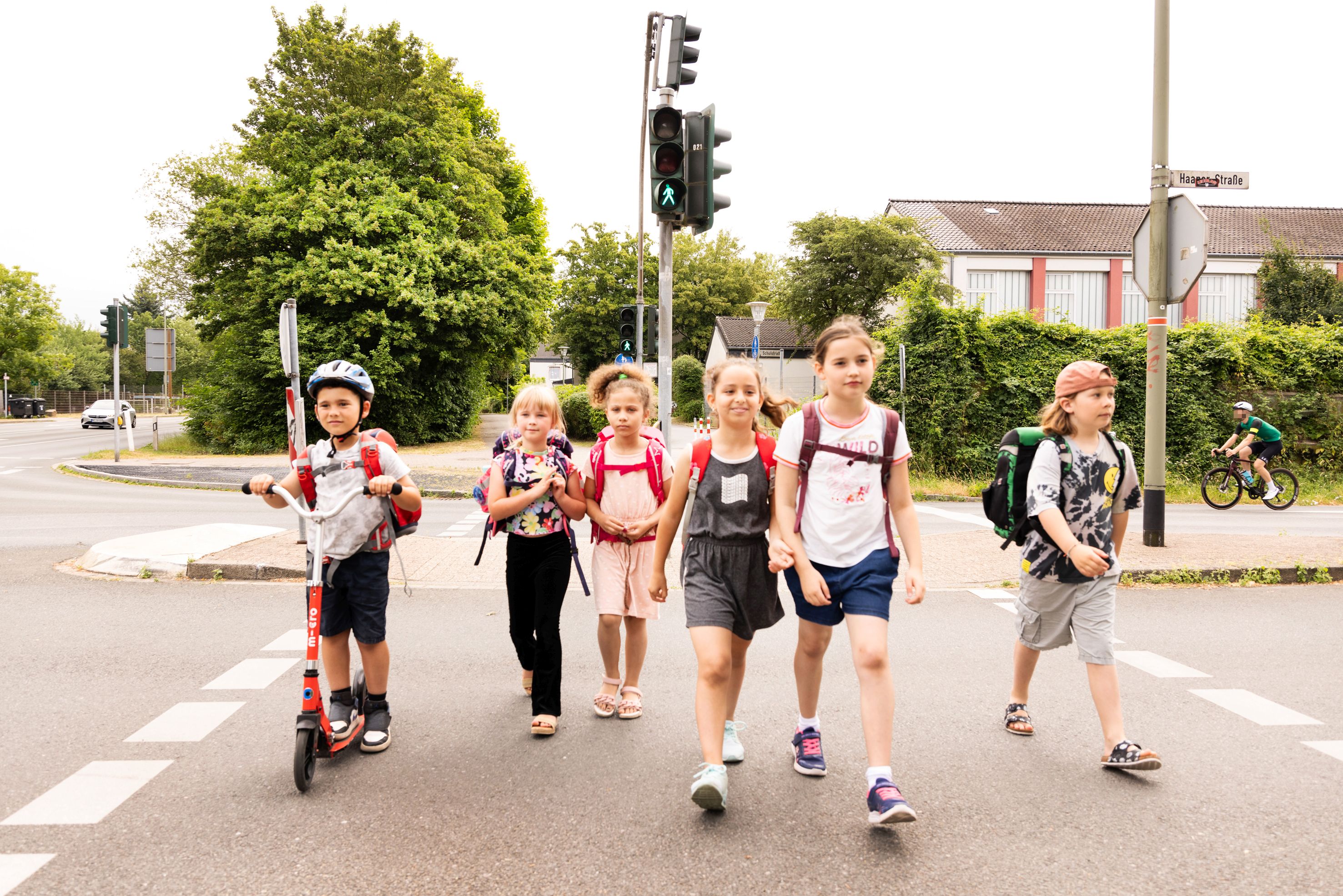 Eine Gruppe Kinder mit Tornistern überquert eine Straße.