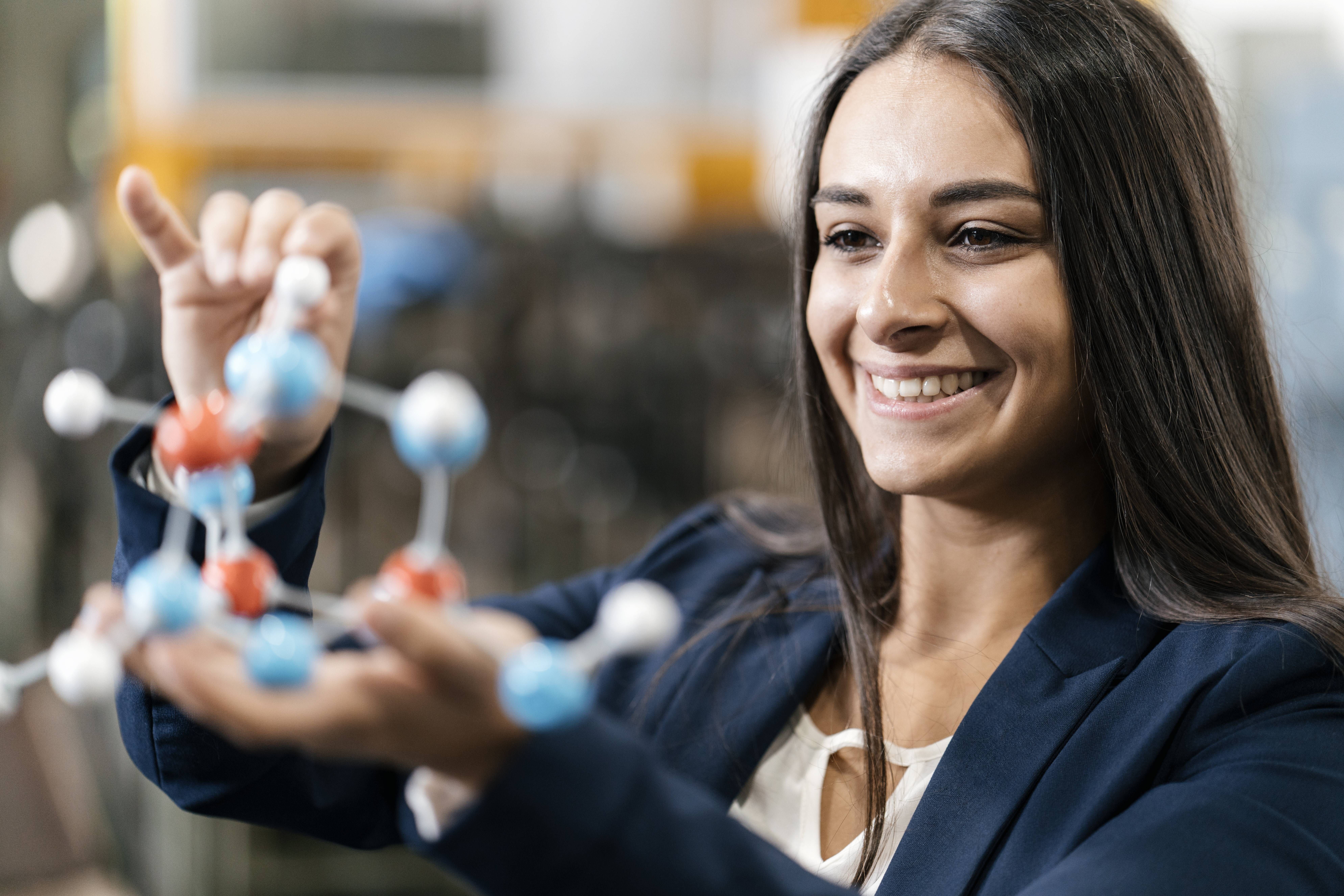 Eine junge Frau betrachtet ein naturwissenschaftliches Modell in ihren Händen.. Eine junge Frau betrachtet ein naturwissenschaftliches Modell in ihren Händen..