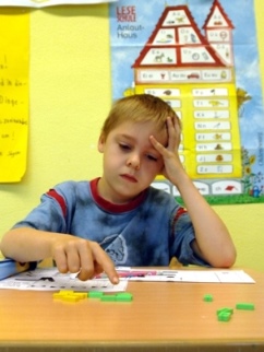 Grundschüler blickt konzentriert auf eine vor ihm liegende Schulaufgabe.