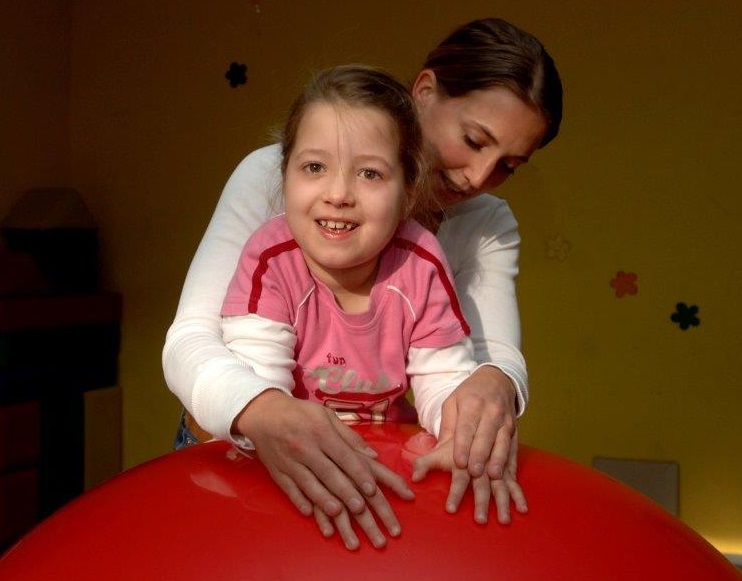 Lehrerin und Schülerin einer Förderschule beim gemeinsamen Ertasten eines großen Balls. Lehrerin und Schülerin einer Förderschule beim gemeinsamen Ertasten eines großen Balls.