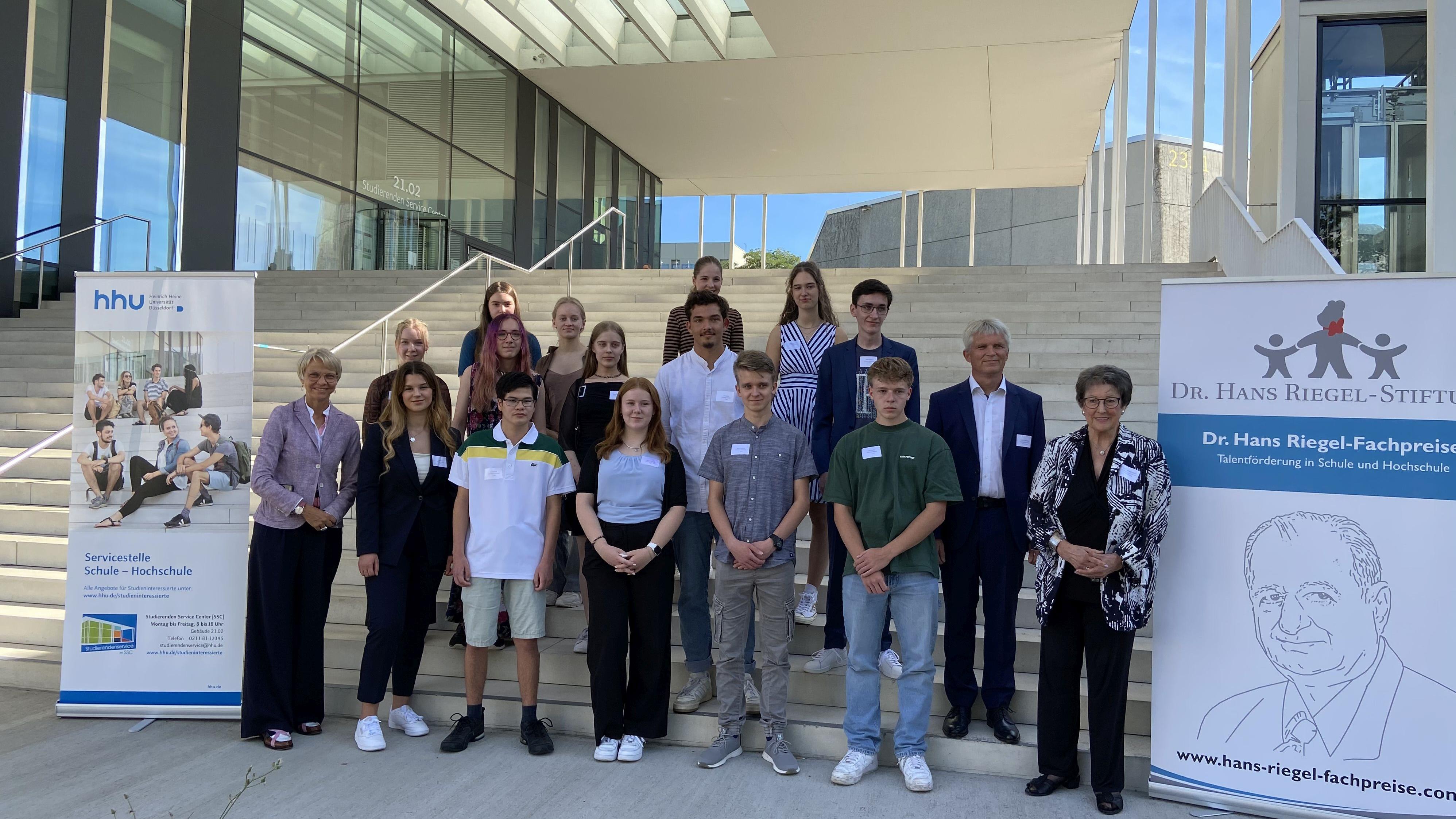 Gruppenbild vor einer Treppe zur Dr. Hans Riegel-Fachpreisverleihung mit Rollups zum Thema