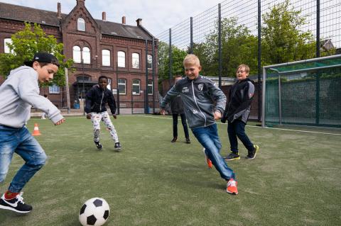 Kinder spielen auf einem Sportplatz Draußen Fußball