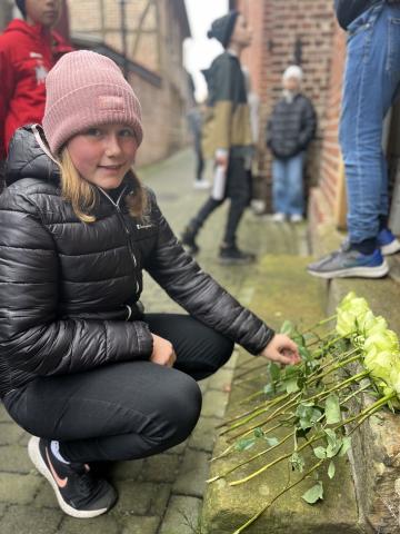 Ein Kind legt am 9. November 2023 zum Gedenken an die jüdischen Opfer des Nationalsozialismus in Drensteinfurt Blumen nieder 