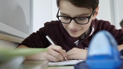 Ein Schüler schreibt in ein Heft.