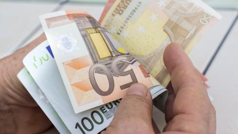 Nahaufnahme zweier Hände, die Euroscheine blättern.