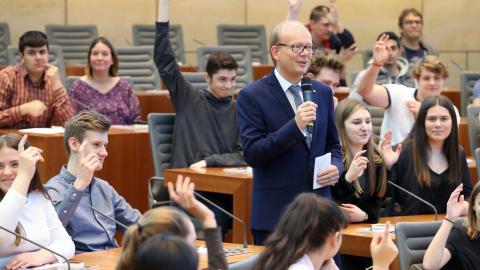 Der Landtagspräsident André Kuper spricht mit Schülerinnen und Schülern.