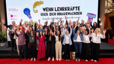 Das Gruppenbild zeigt die Preisträgerinnen und Preisträges des Deutschen Lehrkräftepreises. Sie halten die Hände hoch. 