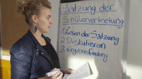 Schülerin steht vor Flipchart - Mitwirkung Schülervertretung