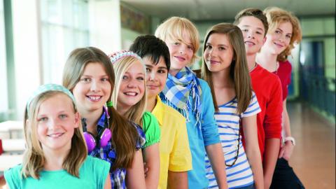 Kinder unterschiedlichen Alters stehen in einer Reihe hintereinander.