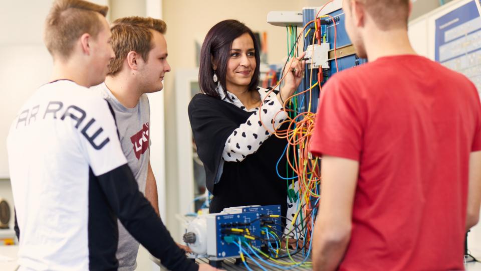 Lehrerin erklärt Schülern im naturwissenschaftlichen Unterricht eine eletronische Aparatur. Lehrerin erklärt Schülern im naturwissenschaftlichen Unterricht eine eletronische Aparatur.