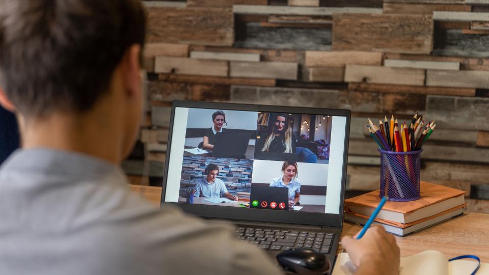 Junge sitzt vor einem Laptop auf dem eine Videokonferenz läuft. Junge sitzt vor einem Laptop auf dem eine Videokonferenz läuft.