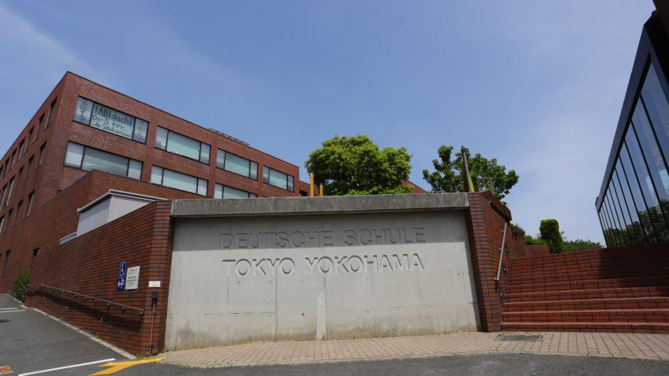 Außenansicht der Deutschen Schule Tokyo Yokohama: ein rotes Schulgebäude vor blauem Himmel