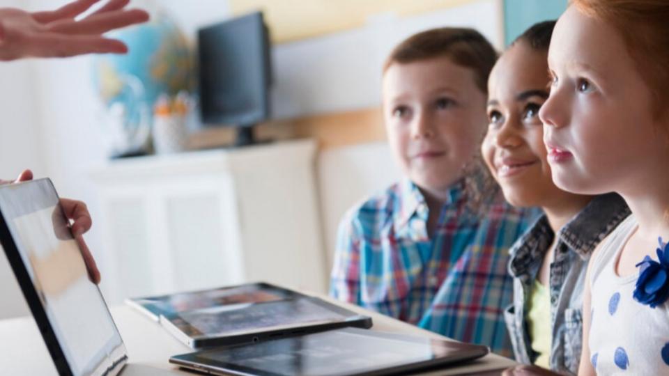 Drei Kinder lernen mit Laptop und Tablet