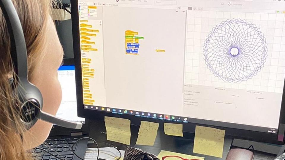 Ein Mädchen sieht am Computer und programmiert