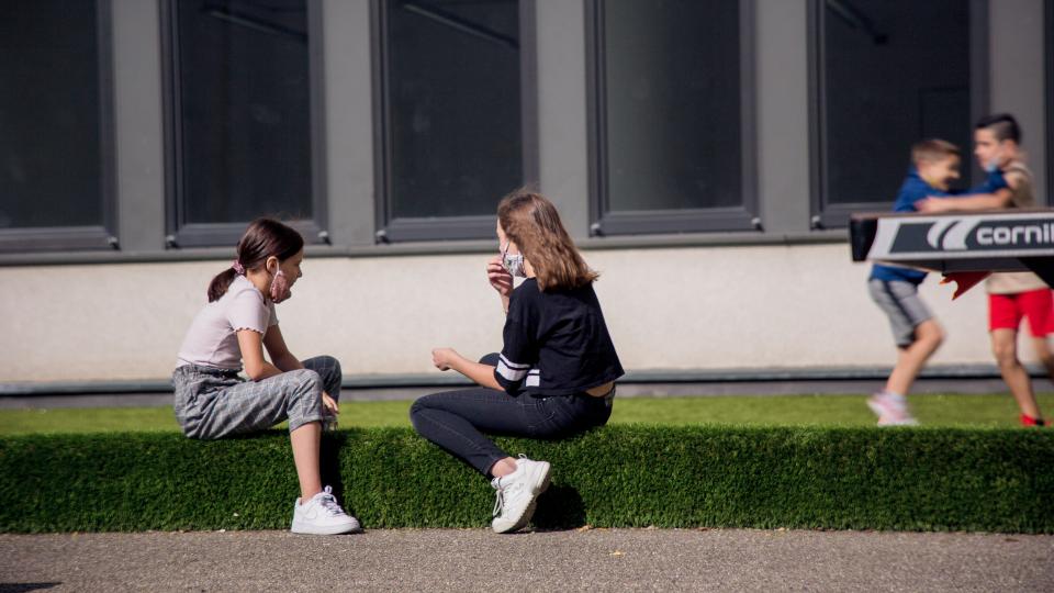 Zwei Schülerinnen unterhalten sich auf dem Schulhof