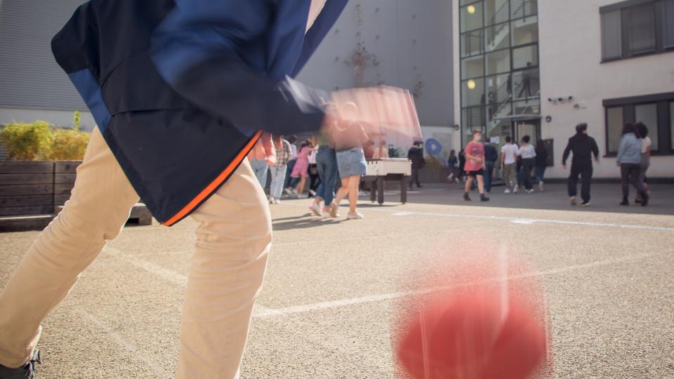 Ein Schüler spielt Basketball auf dem Schulhof