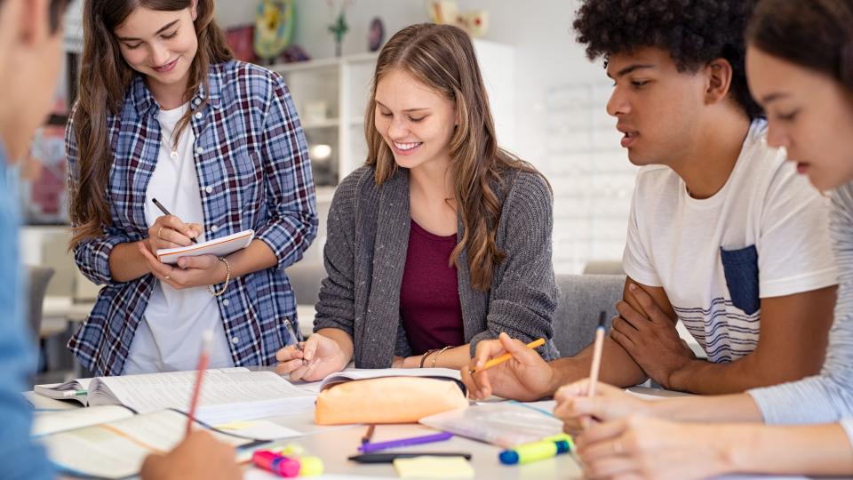 Gruppe von Schülerinnen und Schülern arbeitet gemeinsam an einem Tisch.