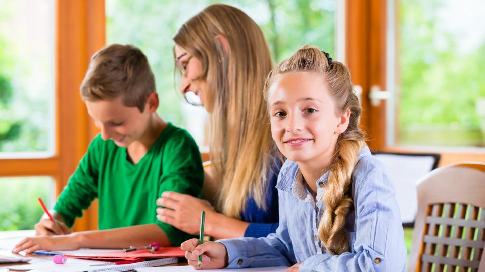 Zwei Kinder arbeiten in einer Lerngruppe zusammen mit einer Lehrerin.