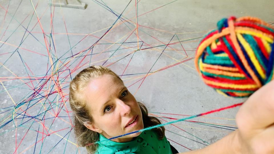 Eine Frau spinnt ein Netzwerk mit bunter Wolle Eine Frau spinnt ein Netzwerk mit bunter Wolle