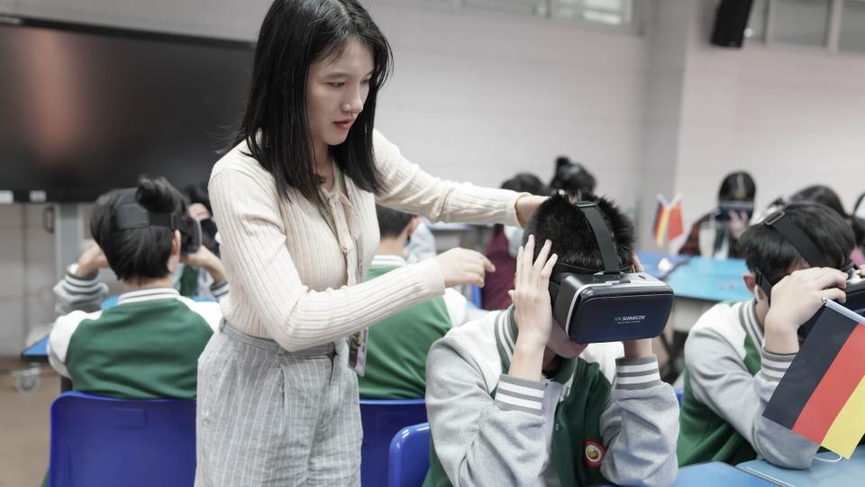 Chinesische Schülerinnen und Schüler tauschen sich digital mit VR-Brillen mit Gleichaltrigen in Deutschland aus.