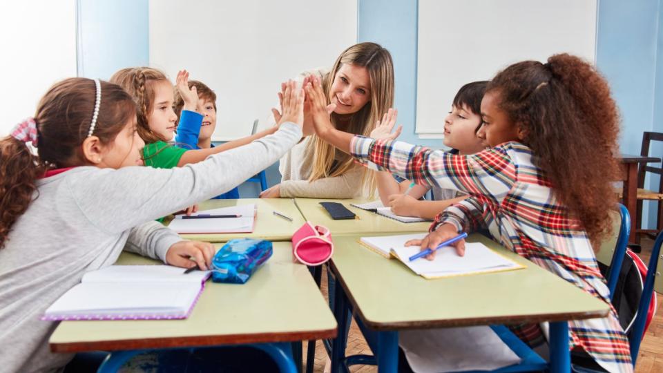 Eine Lerngruppe sitzt mit ihrer Lehrerin am Tisch.