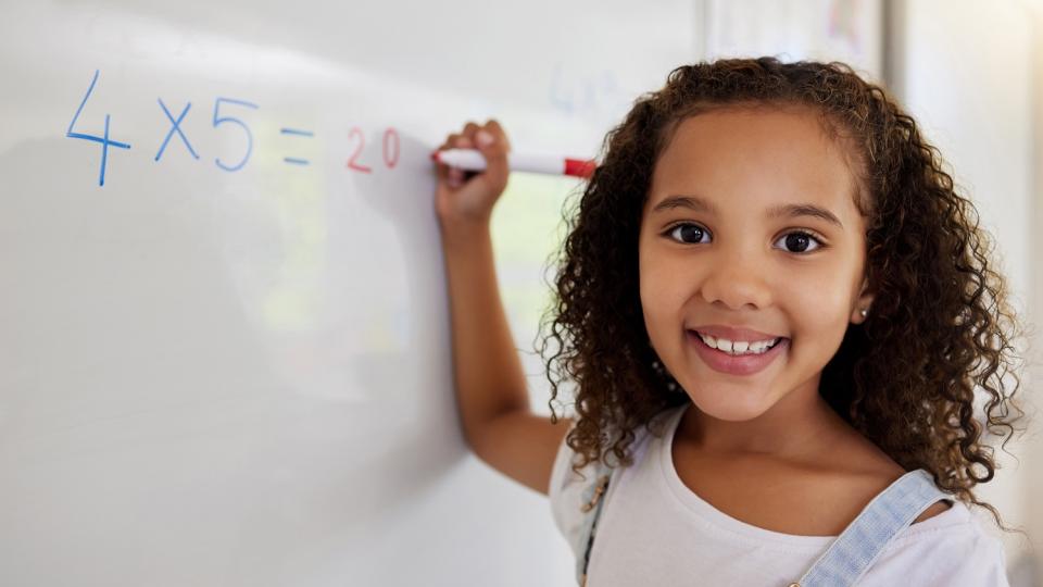 Mädchen schreibt eine Rechenaufgabe an ein Whiteboard. Mädchen schreibt eine Rechenaufgabe an ein Whiteboard.