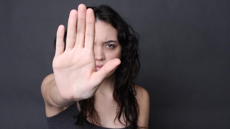 Jugendliche streckt die rechte Hand in abwehrender Geste aus. Jugendliche streckt die rechte Hand in abwehrender Geste aus.