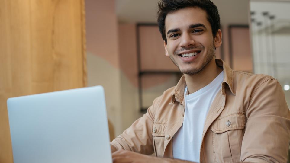 Ein Mann sitzt vor einem geöffneten Laptop und schreibt etwas. Ein Mann sitzt vor einem geöffneten Laptop und schreibt etwas.