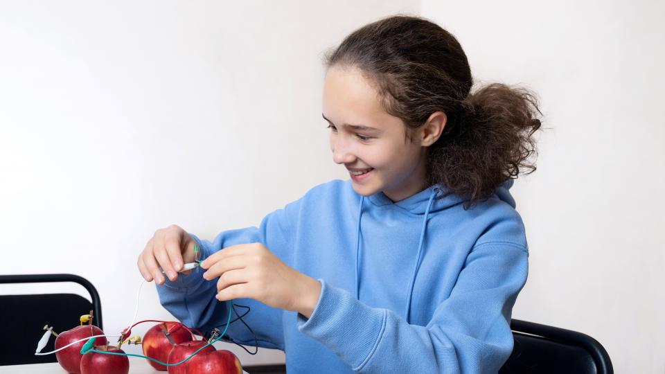 Ein Mädchen experimentiert mit Äpfeln und Kabeln. Ein Mädchen experimentiert mit Äpfeln und Kabeln.