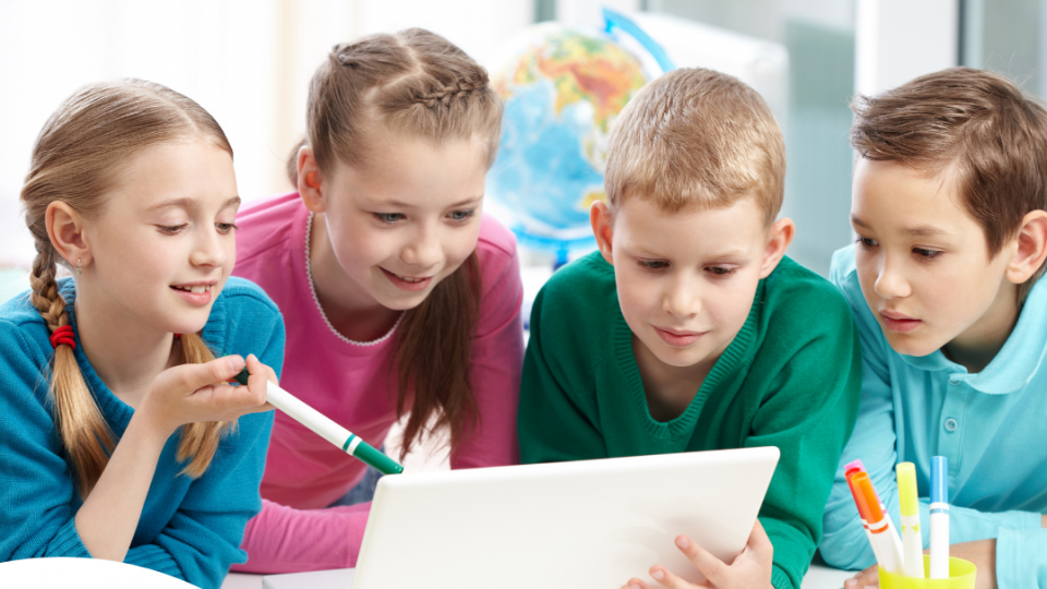 Vier Kinder schauen gemeinsam auf einen Laptop Vier Kinder schauen gemeinsam auf einen Laptop