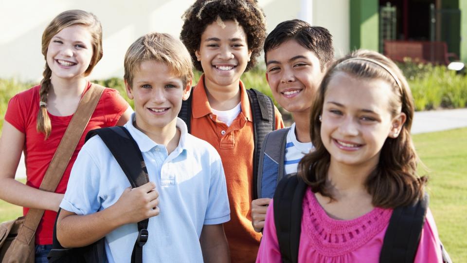 Eine Gruppe Schülerinnen und Schüler stehen auf einer Wiese vor einem Gebäude.