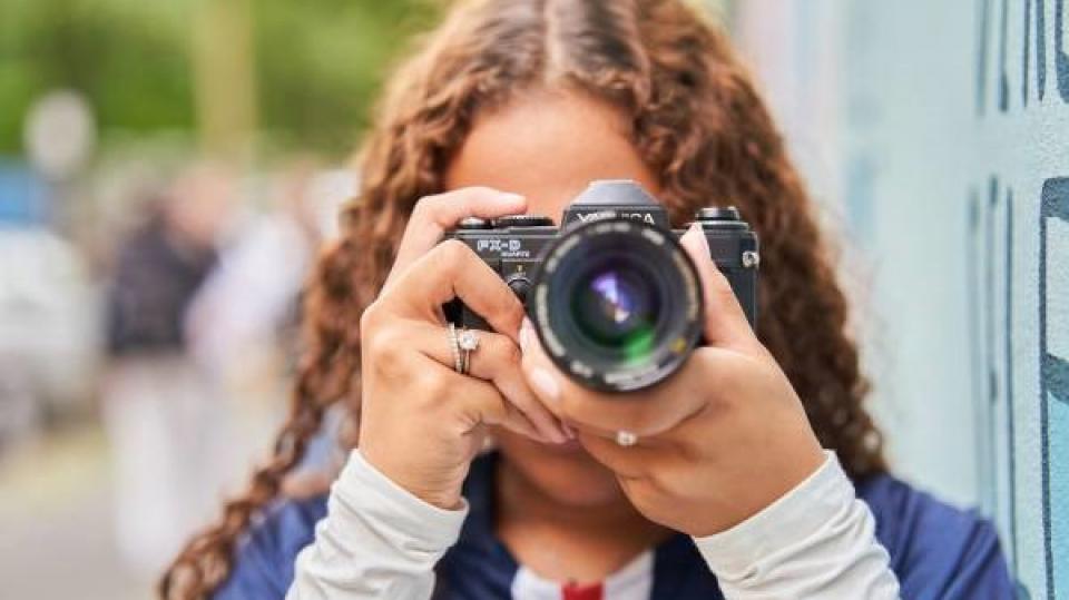 Eine junge Frau nimmt ein Foto mit einer Kamera auf.