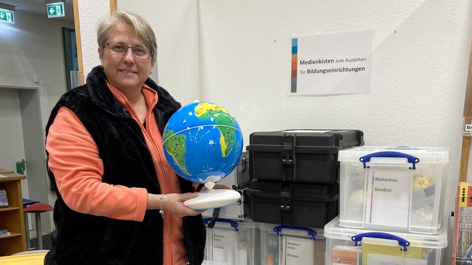 Bibliothekarin Dagmar Schnittker steht vor den Medienkisten in der Ibbenbürener Stadtbibliothek.