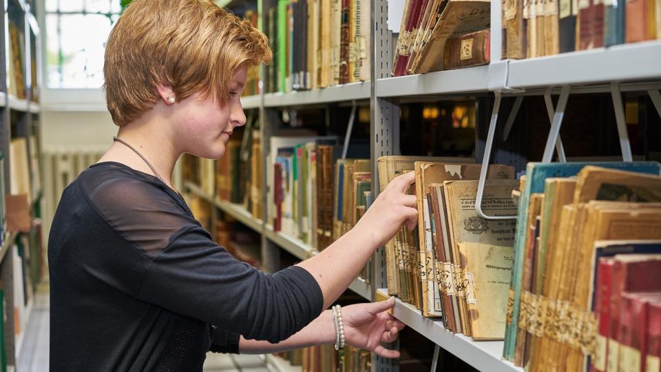 Eine Schülerin schaut sich Archivalien an Eine Schülerin schaut sich Archivalien an