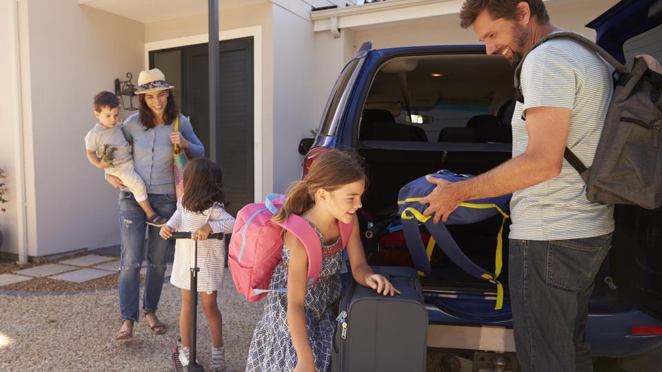 Eine Familie packt Koffer und Taschen in den Kofferraum eines Autos. Eine Familie packt Koffer und Taschen in den Kofferraum eines Autos.
