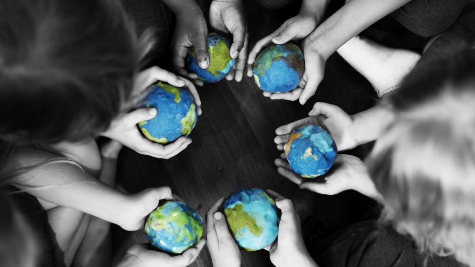 Eine Gruppe Kinder hält kleine Weltkugeln in den Händen. Eine Gruppe Kinder hält kleine Weltkugeln in den Händen.