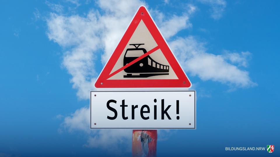 Straßenschild vor blauem Himmel mit der grafischen Darstellung eines durchgestrichenen Zuges. Darunter steht auf einem Schild "Streik!".