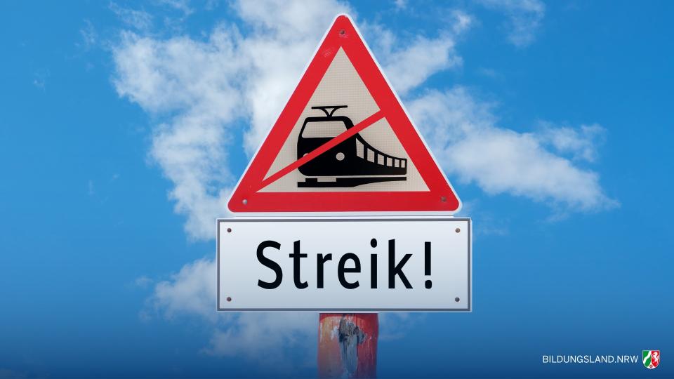 Straßenschild vor blauem Himmel mit der grafischen Darstellung eines durchgestrichenen Zuges. Darunter steht auf einem Schild "Streik!". Straßenschild vor blauem Himmel mit der grafischen Darstellung eines durchgestrichenen Zuges. Darunter steht auf einem Schild "Streik!".