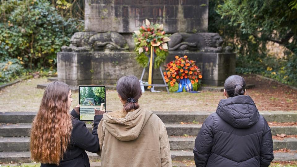 Jugendliche stehen vor einem Gefallenendenkmal. Jugendliche stehen vor einem Gefallenendenkmal.