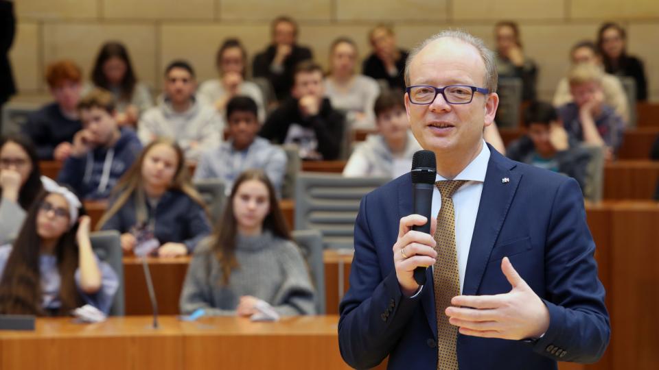 Die Landtagspräsident André Kuper spricht zu Schülerinnen und Schülern.
