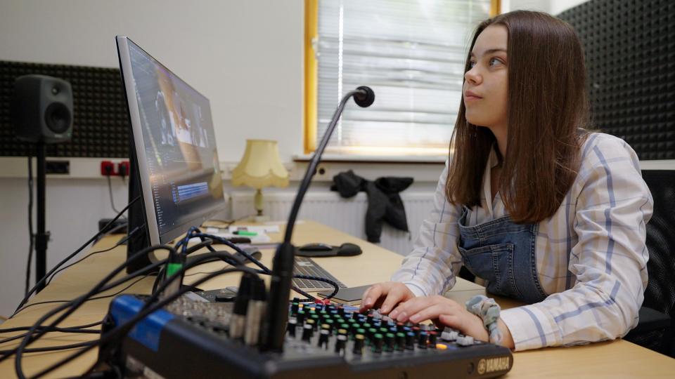 Ein Mädchen sitzt in einem Tonstudio vor einem Bildschirm. Ein Mädchen sitzt in einem Tonstudio vor einem Bildschirm.