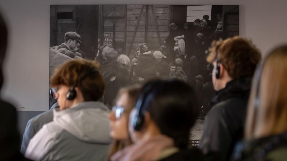 Fotos in der Ausstellung zeigen den Prozess der Ankunft in Auschwitz-Birkenau: Schülerinnen und Schüler in der Ausstellung in einem der Gebäude im Stammlager Auschwitz I