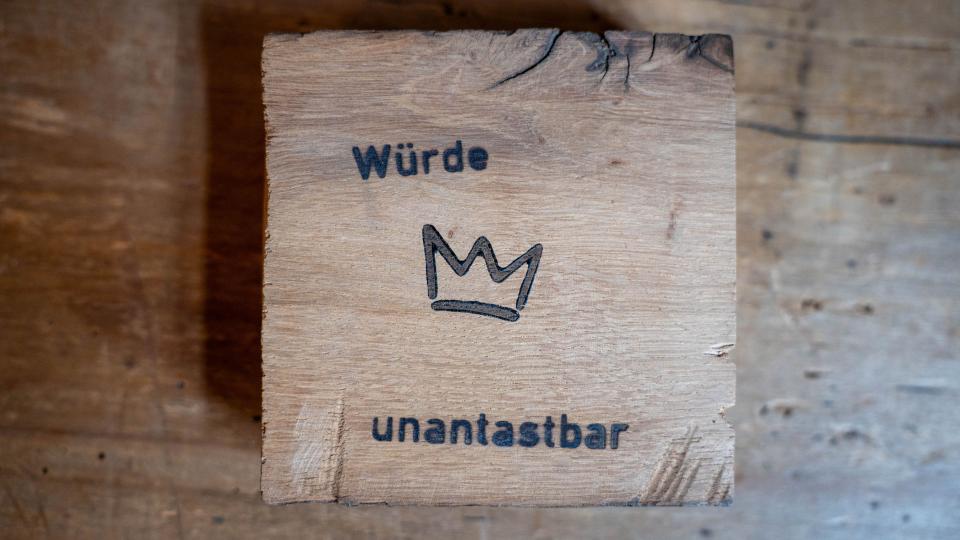 Eine sogenannte "Würdetafel" ist ein Holzquadrat mit einer Krone und der Aufschrift "Würde unantastbar". Eine sogenannte "Würdetafel" ist ein Holzquadrat mit einer Krone und der Aufschrift "Würde unantastbar".