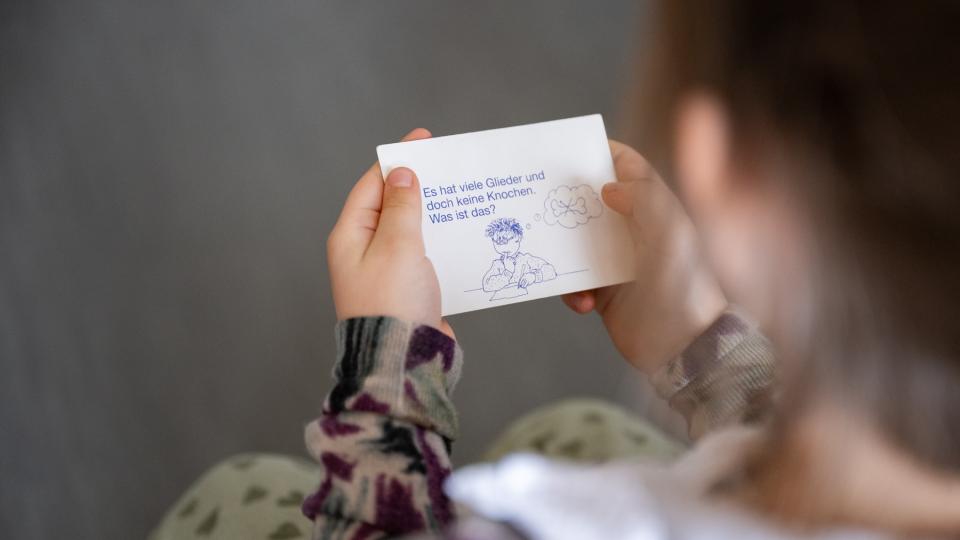 Eine Schülerin aus der Sprachfördergruppe hält eine Rätselkarte in der Hand.