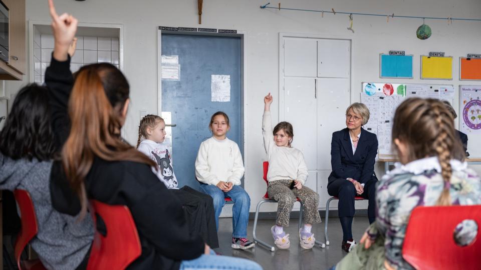 Die Schülerinnen und Schüler der Sprachfördergruppe der Bonifatiusschule Düsseldorf sitzen mit Ministerin Feller im Stuhlreis.