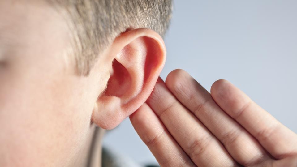 Nahaufnahme eines Kindes, das sich die Hand hinter das Ohr hält. Nahaufnahme eines Kindes, das sich die Hand hinter das Ohr hält.
