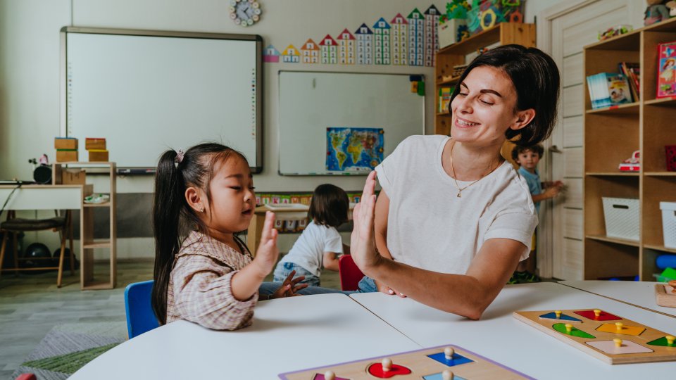 Ein Kind und eine Erwachsene sitzen an einem Tisch mit Spielen. Ein Kind und eine Erwachsene sitzen an einem Tisch mit Spielen.