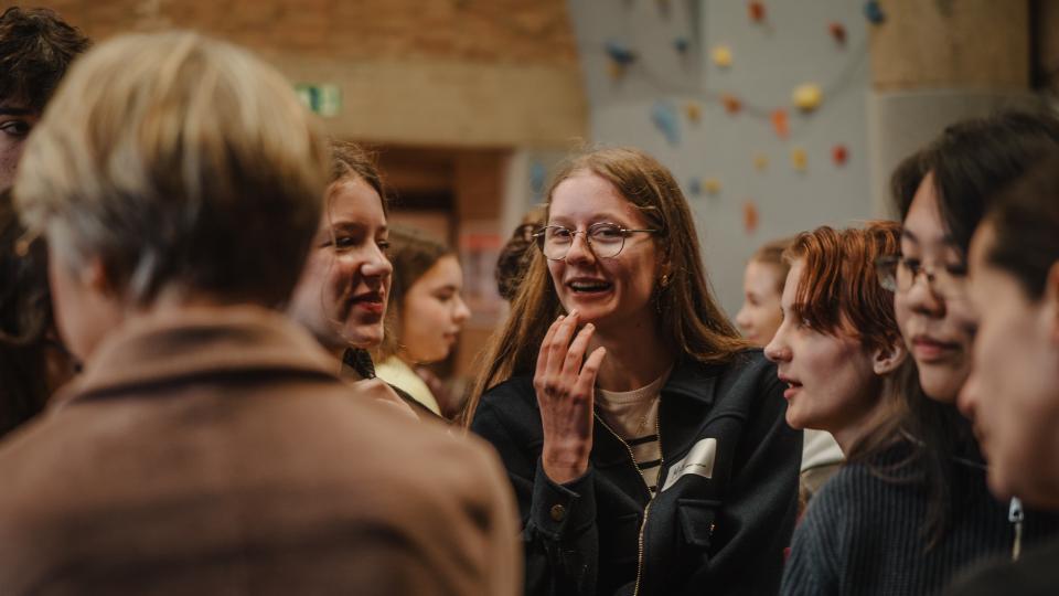 Schulministerin Feller unterhält sich mit mehreren Jugendlichen in einer Turnhalle