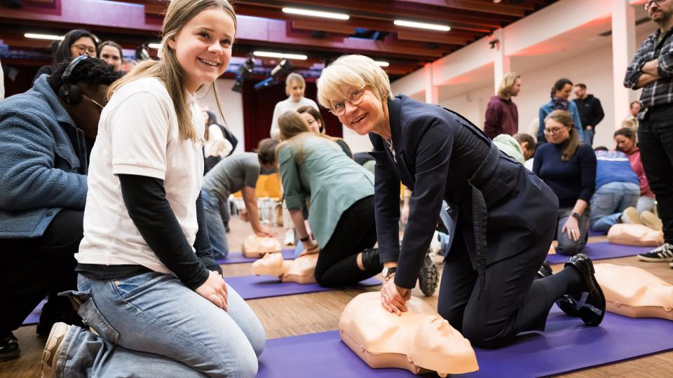 Ministerin Feller demonstriert Reanimation an einer Puppe.