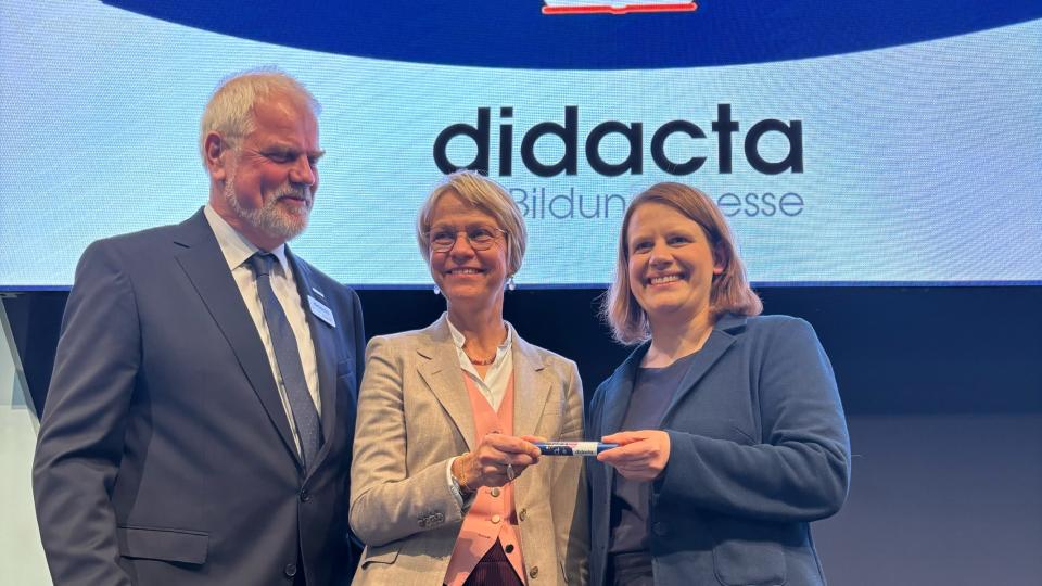 Schul- und Bildungsministerin Dorothee Feller übergibt bei der didacta 2026 symbolisch den Staffelstab an die niedersächsische Kultusministerin Julia Willie Hamburg begleitet durch Dr. Hans-Joachim Prinz, Präsident des didacta Verbands.